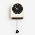 Horloge à pendule moderne crème avec détails noirs et cadran minimaliste sur fond blanc.