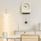 Horloge à pendule moderne crème installée dans un salon au style bohème avec une table en rotin et décoration minimaliste.