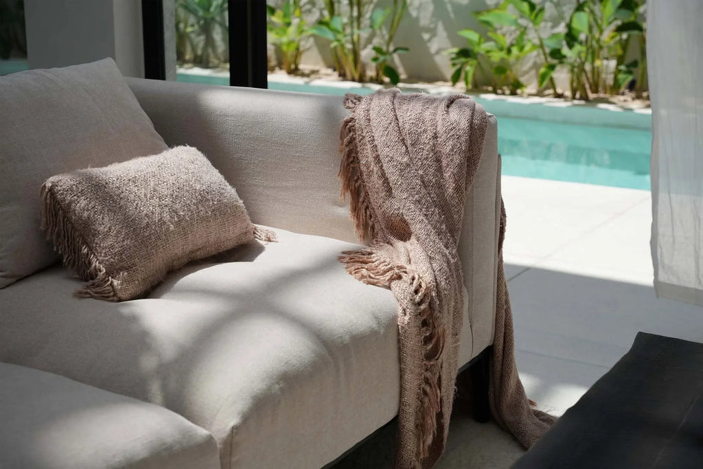 Couverture jetable beige texturée à franges sur canapé clair