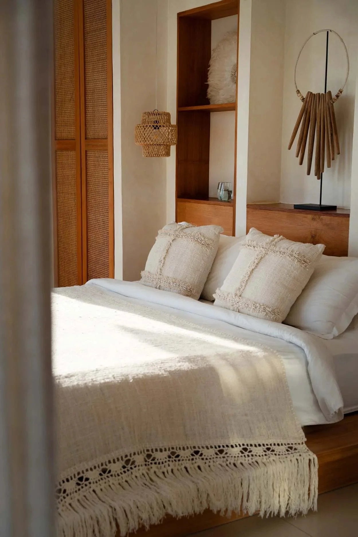 Housse de coussin carrée beige en tissu texturé avec franges et coquillages, idéale pour un style bohème