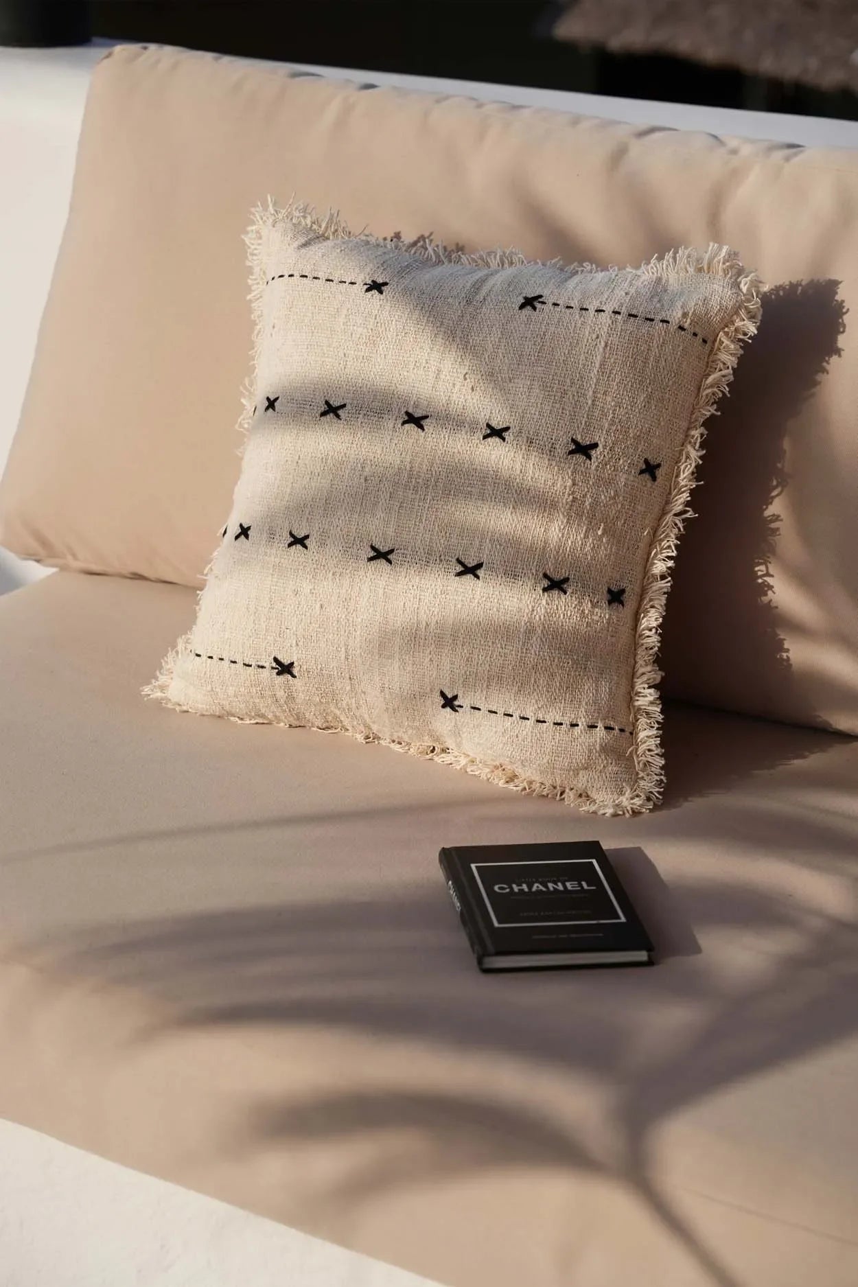 Coussin carré en coton beige avec broderie noire et franges, décoration élégante