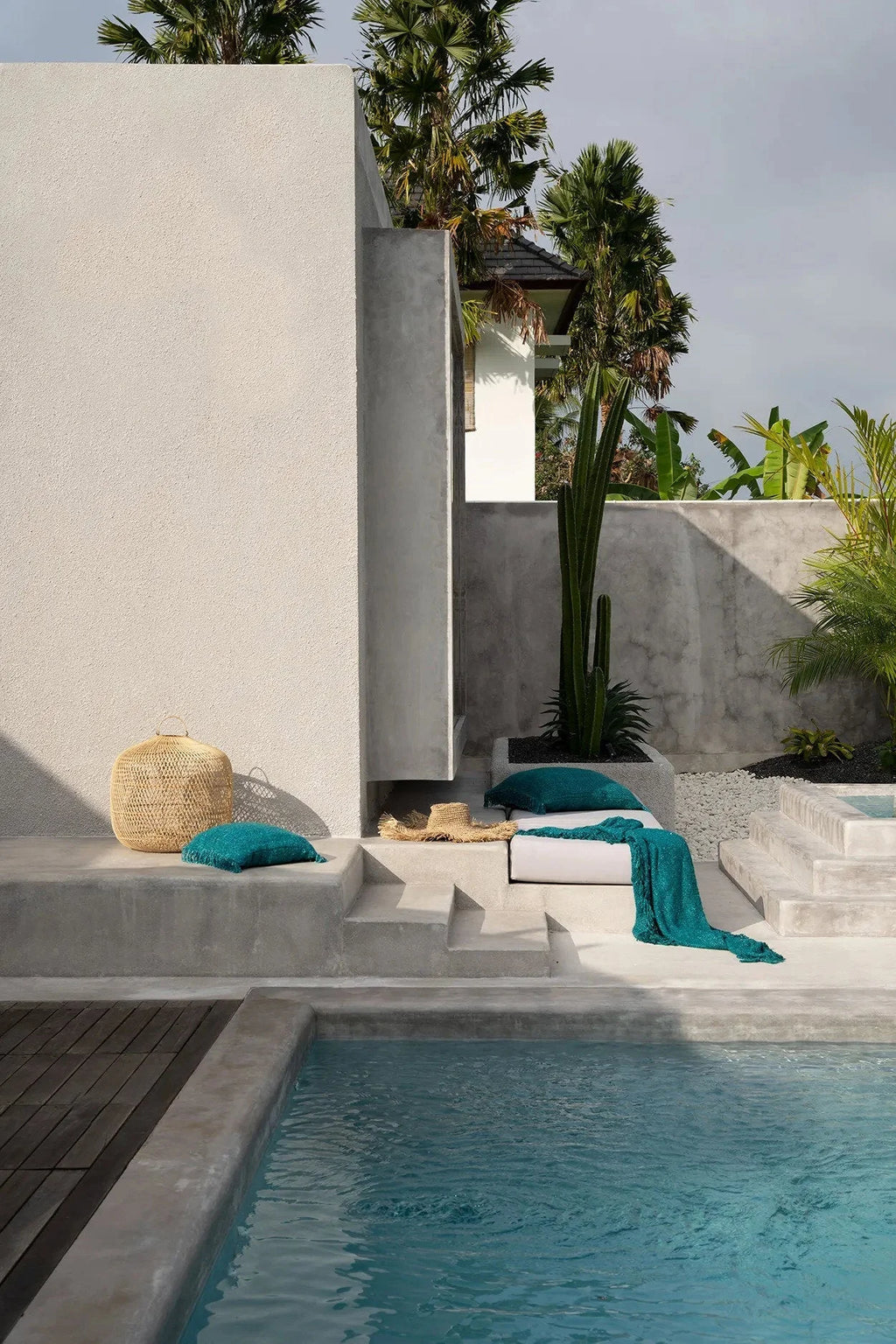 Housse de coussin carrée en coton texturé aqua avec franges sur une terrasse de piscine moderne