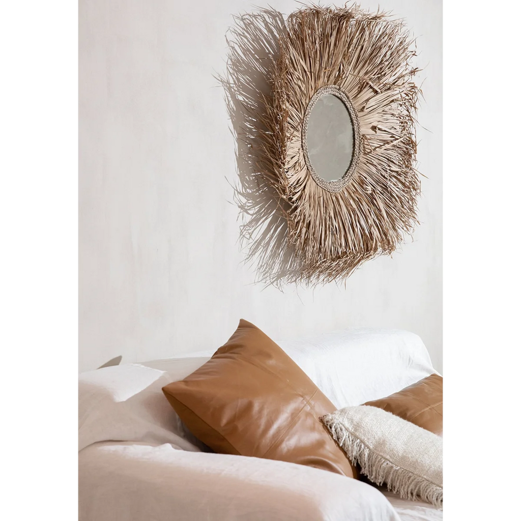 Miroir rond avec cadre en feuilles de palmier séchées naturel dans la pièce
