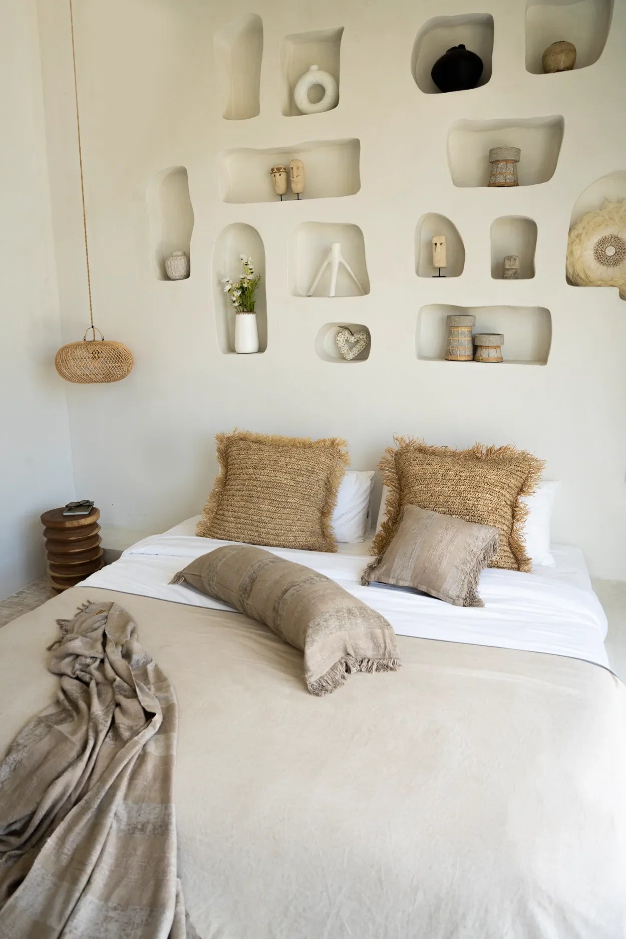 Housse de coussin carrée en raphia naturel dans une chambre neutre avec niches murales