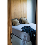 Mur en panneaux de bois avec lit blanc et couverture bleue en raphia tressé