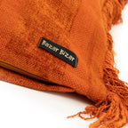 Coussin carré en velours rouille avec franges et étiquette pour décoration intérieure