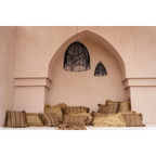 Suspension en osier noir dans une alcôve avec coussins rayés et pailles pour la déco