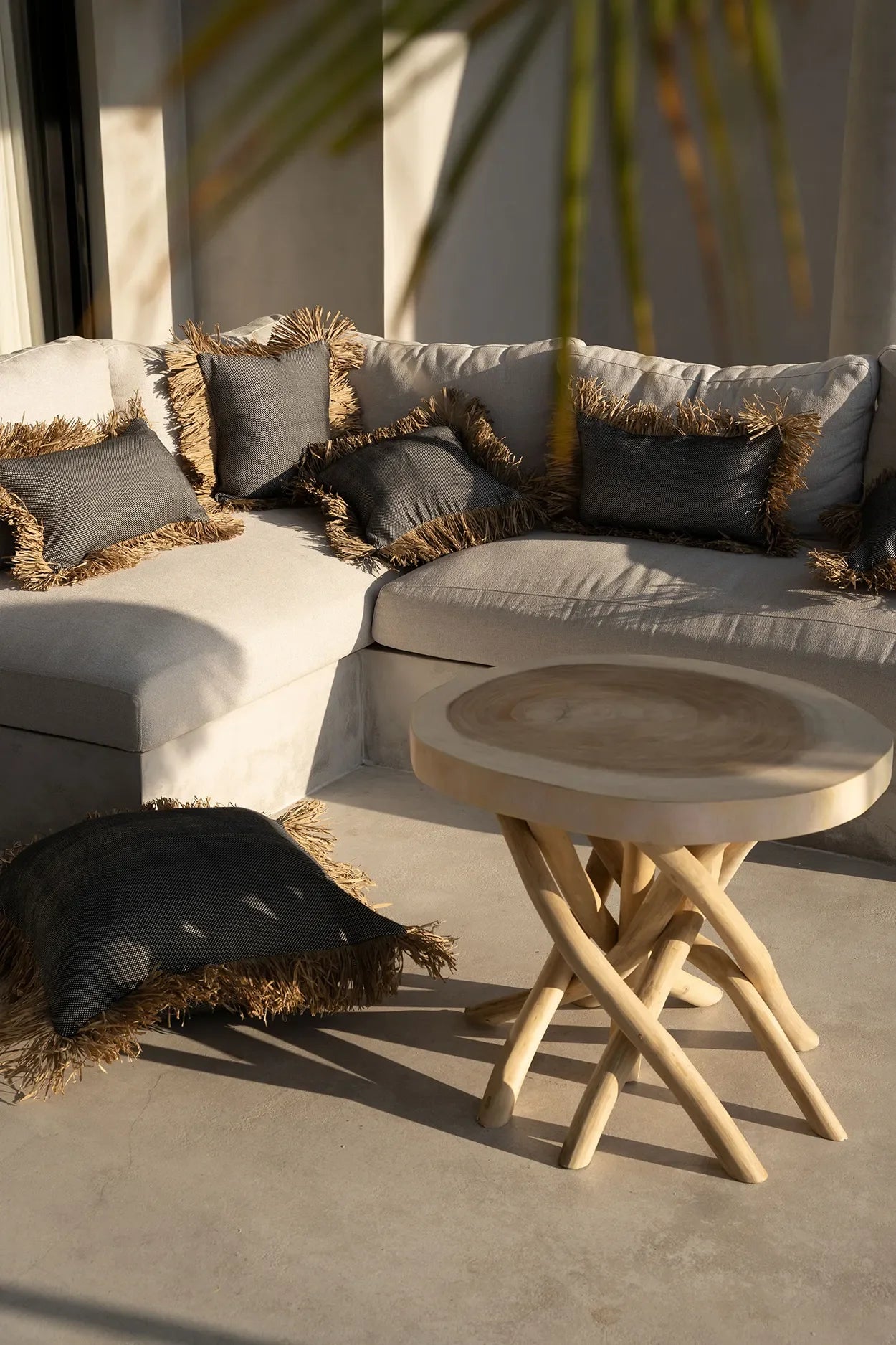 Housse de coussin coton et raphia noir naturel 30x50 sur canapé blanc avec coussins fringés