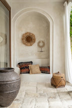 Housse de coussin en coton noir et orange avec motif ethnique dans une alcôve rustique