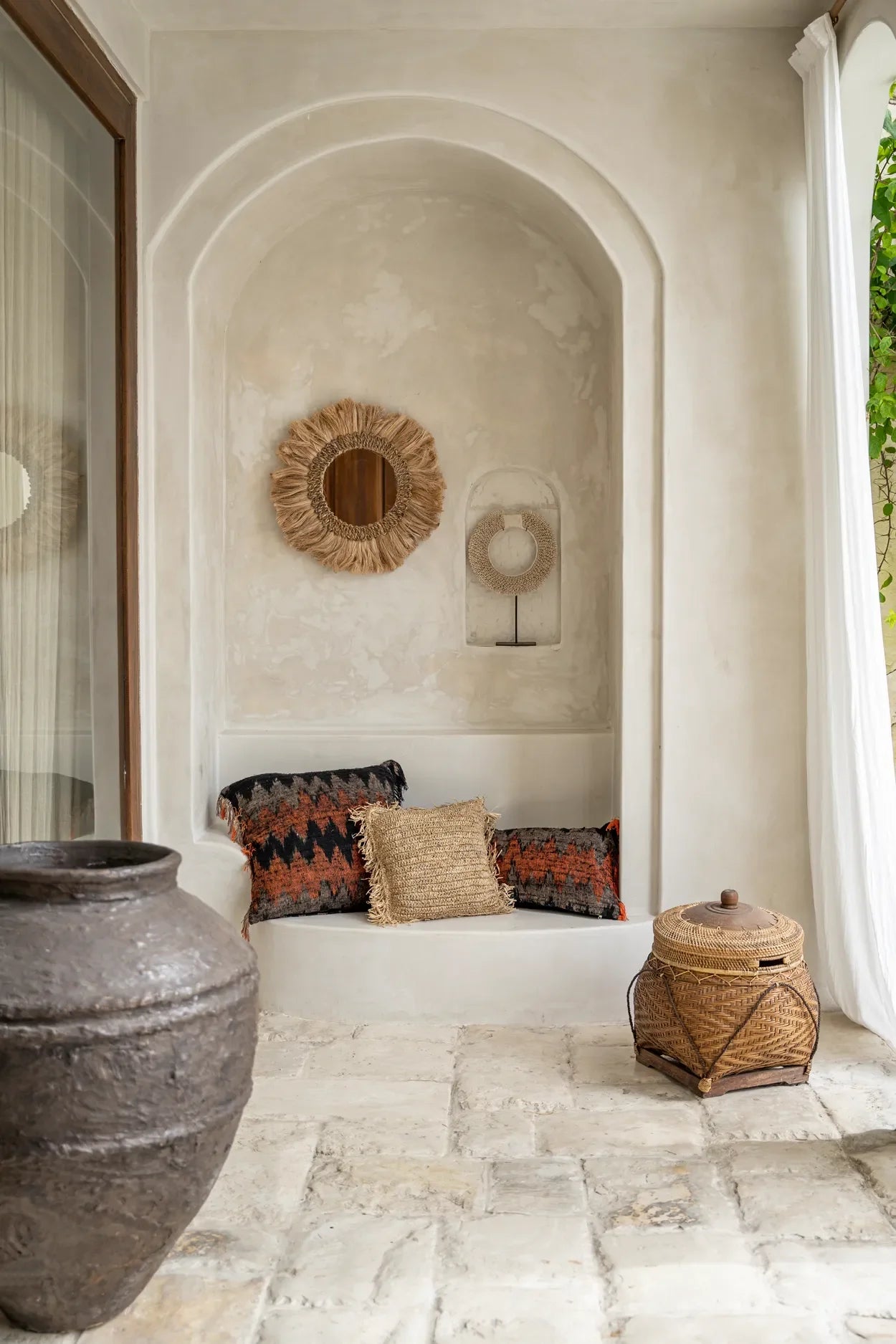 Housse de coussin en coton noir et orange avec motif ethnique dans une alcôve rustique