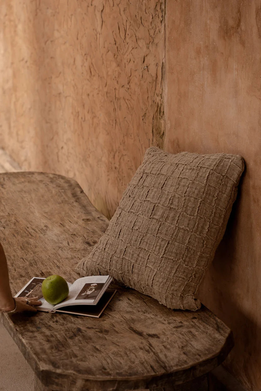 Housse de coussin en lin beige à carreaux relief texturés contre mur rustique