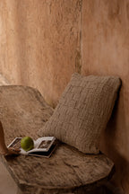 Housse de coussin en lin beige à carreaux relief texturés contre mur rustique