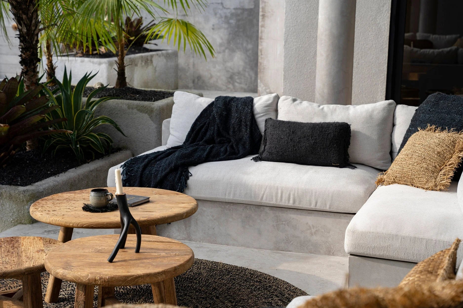 Housse de coussin noire en coton avec franges sur un canapé d’extérieur blanc