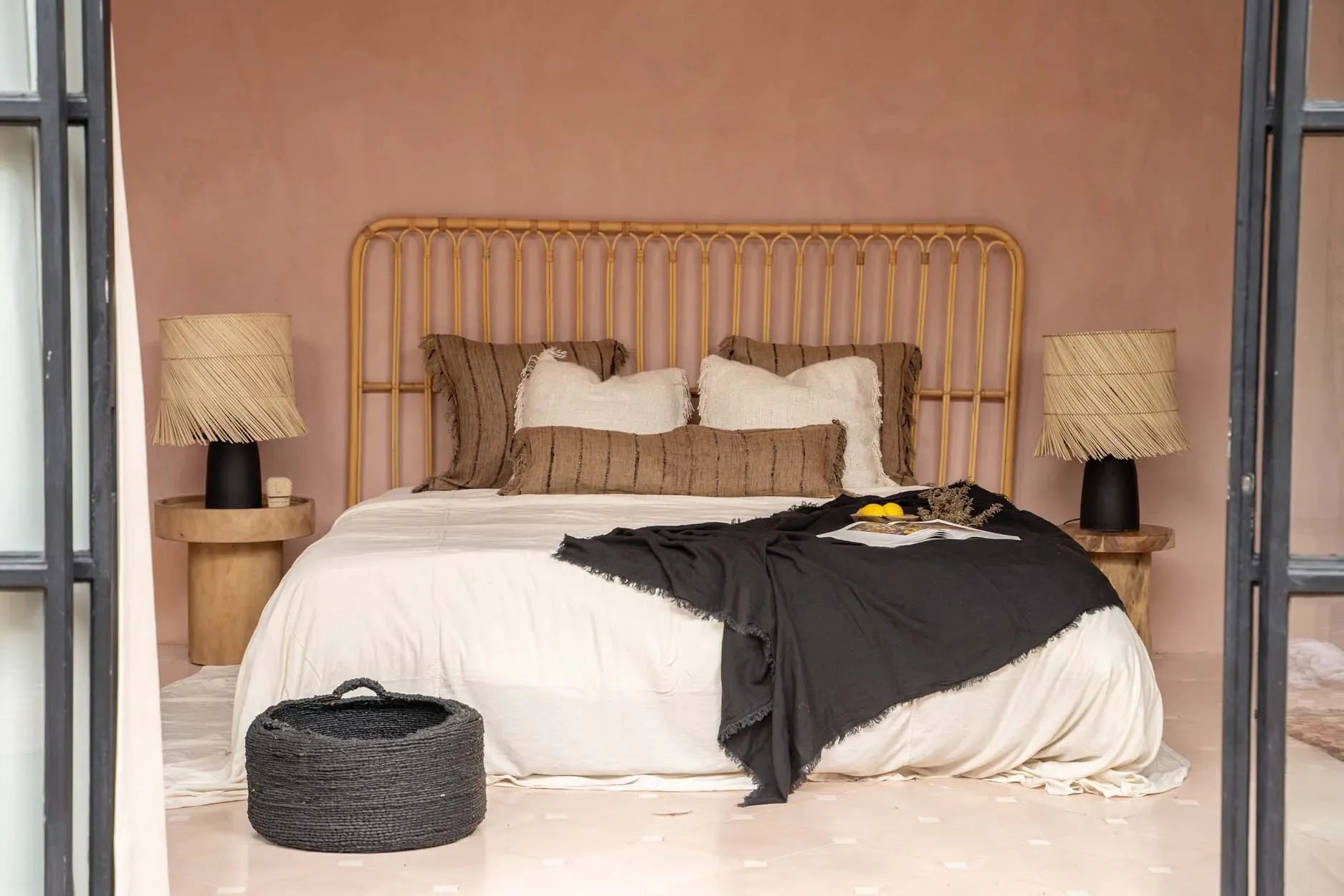 Housse de coussin rectangulaire en coton beige et noir à franges dans une chambre bohème avec tête de lit en rotin