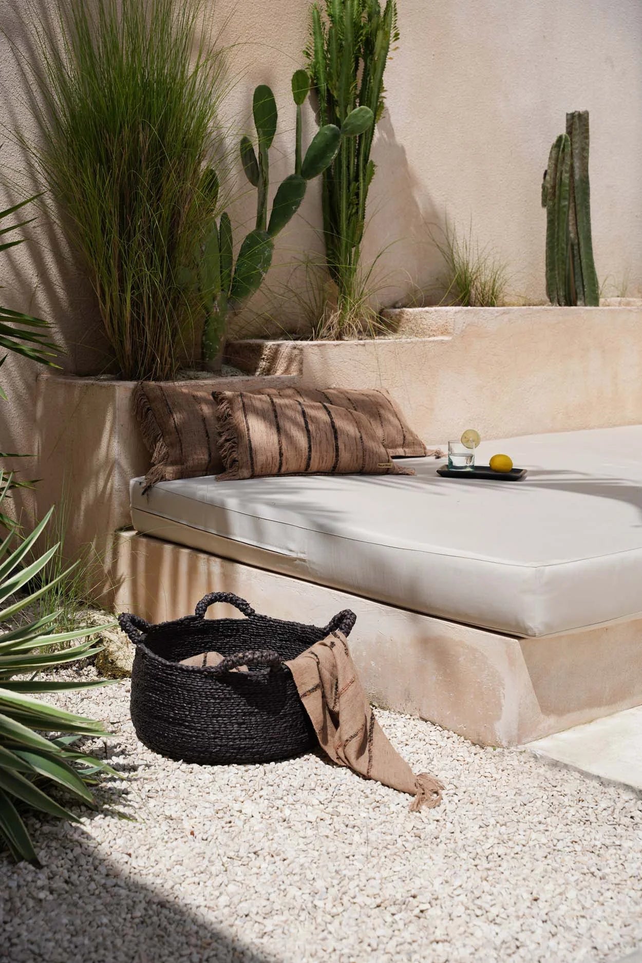 Panier tissé noir dans un coussin rectangulaire en coton beige et noir à franges