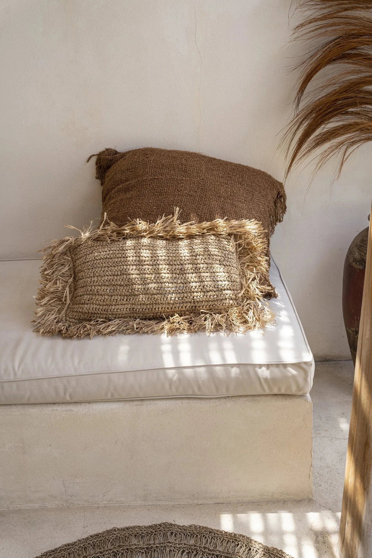 Deux coussins en raphia naturel avec franges, un brun et un beige clair