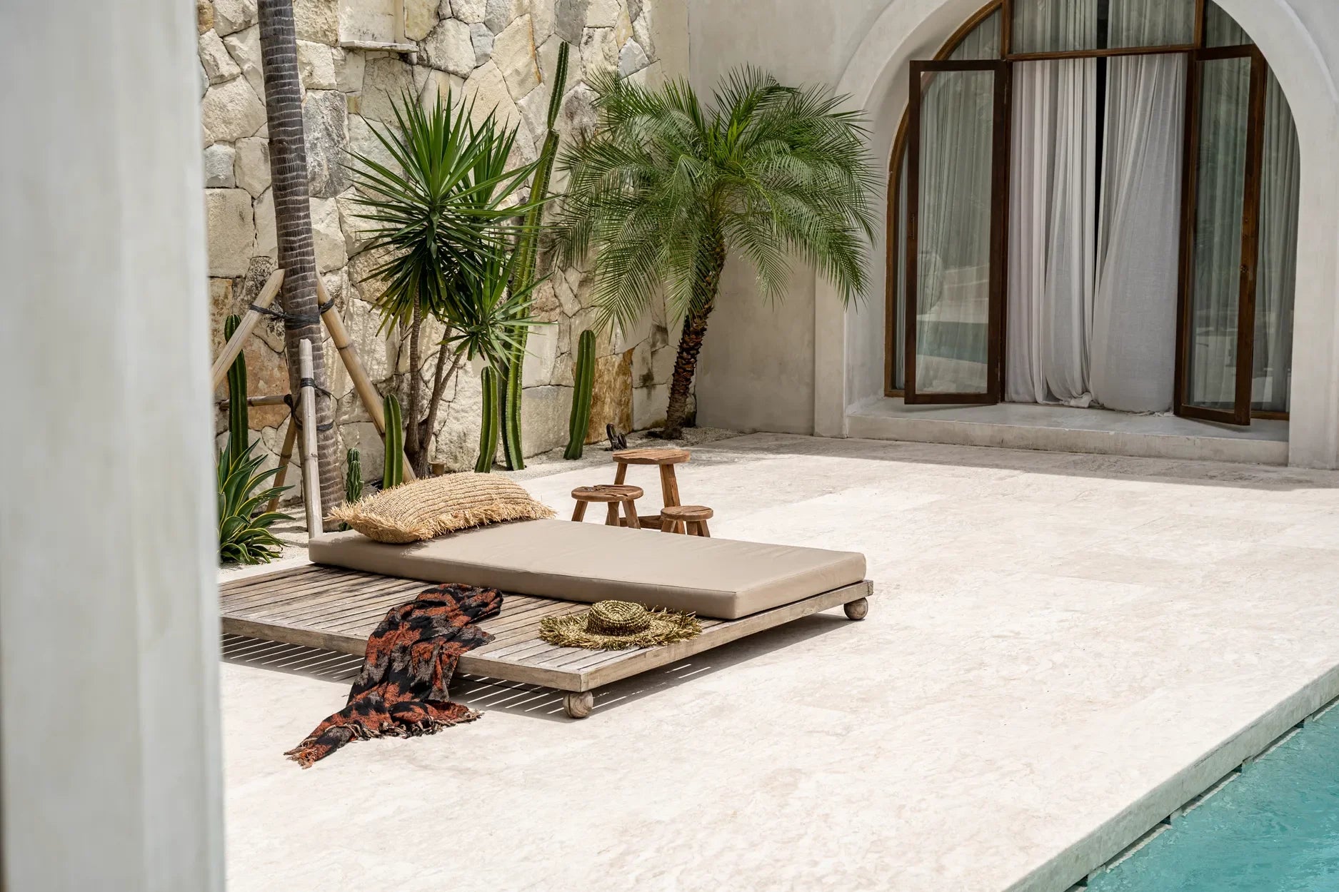 Housse de coussin rectangulaire en raphia naturel avec franges sur un outdoor daybed avec oreiller et chapeau