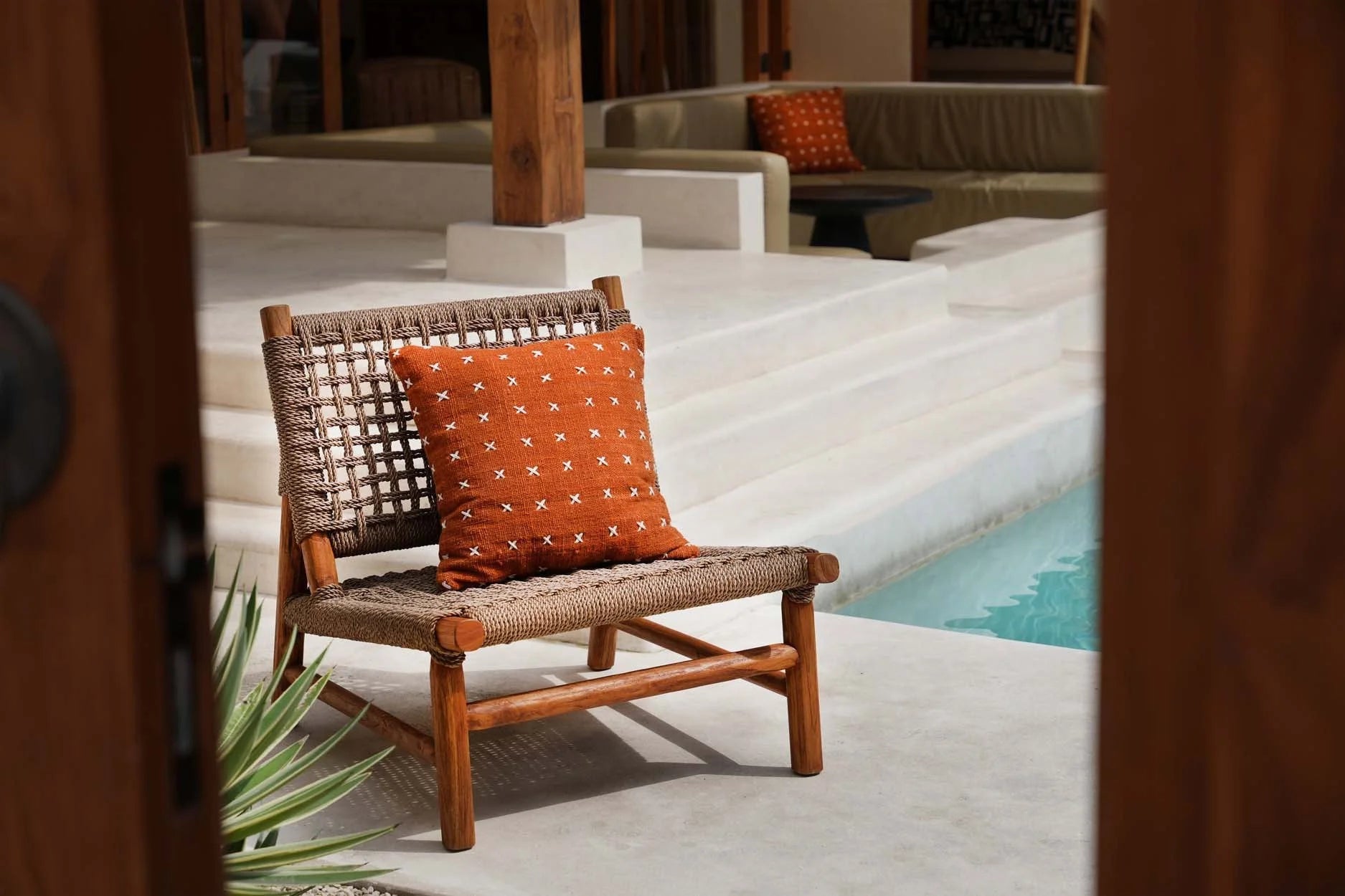 Fauteuil lounge d’extérieur en osier avec coussin décoratif terracotta brodé en coton