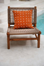 Chaise en bois avec coussin orange brodé en coton motif croix blanches 50x50 cm