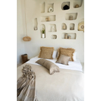 Housse de coussin en velours béton 40x40 cm sur un lit avec duvet et coussins