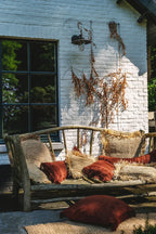 Housse de coussin en velours bordeaux rayé à franges sur un banc en bois rustique