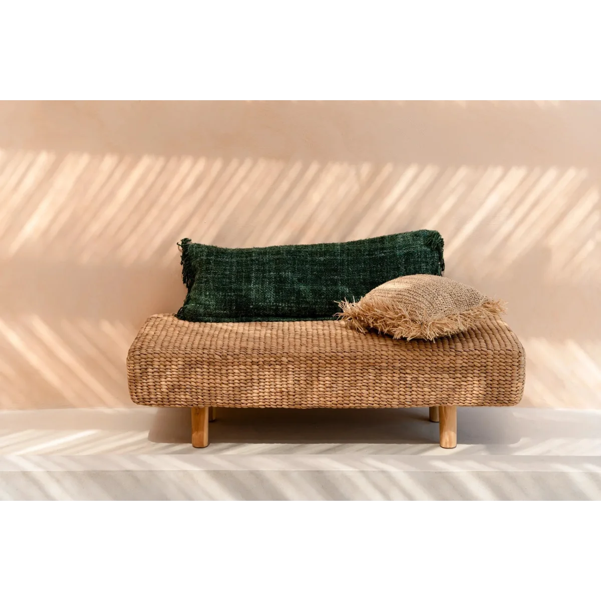 Banquette en rotin tissé avec deux coussins décoratifs verts forêt en coton