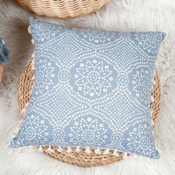 Housse de coussin bleu géométrique avec franges et motifs en situation dans un salon