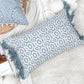 Housse de coussin bleu géométrique avec franges posée sur un canapé