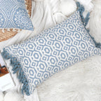 Housse de coussin bleu géométrique avec franges posée sur un canapé