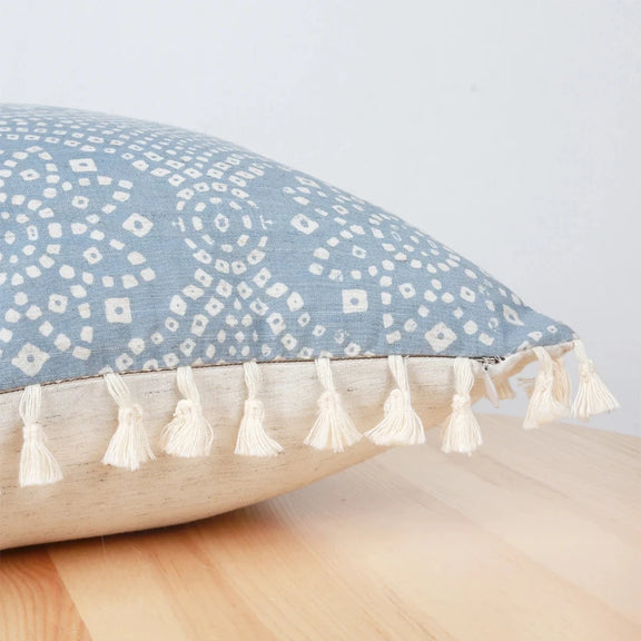Zoom sur les détails des motifs géométriques et franges de la housse de coussin bleu