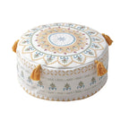 Housse de pouf rond avec un motif jaune et blanc, ornée de pompons, pour une décoration bohème et lumineuse.