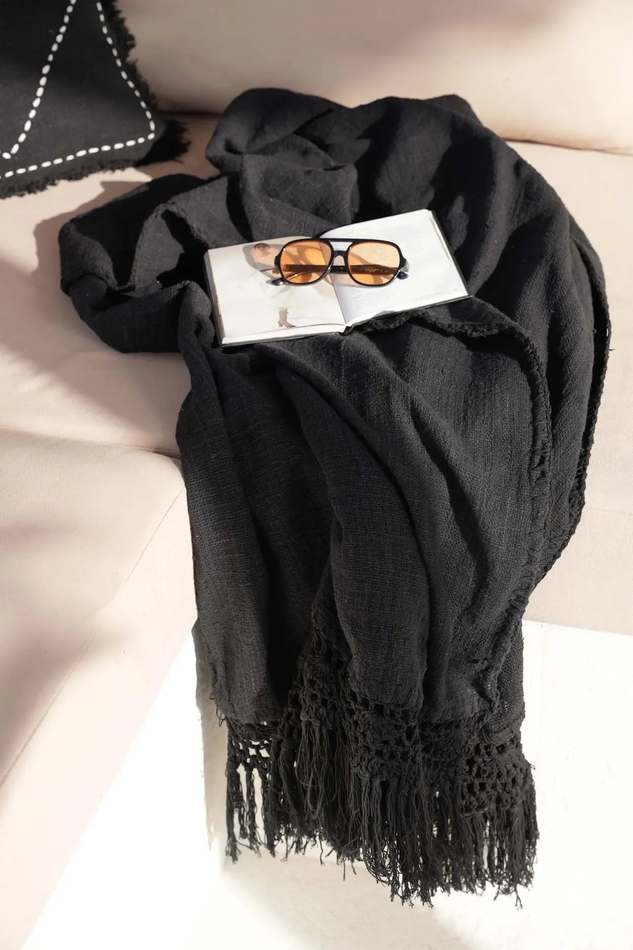 Jeté de lit en coton noir avec franges, livre et lunettes de soleil pour un style décontracté
