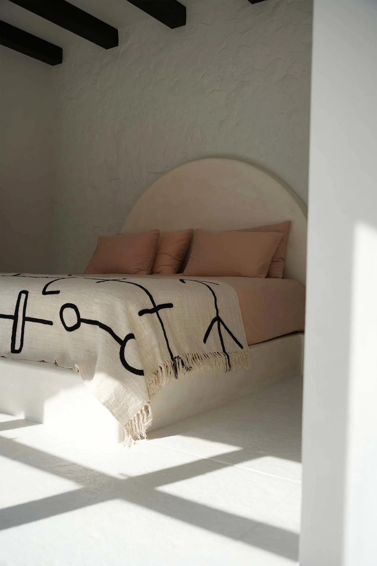 Chambre minimaliste avec jeté de lit en coton noir naturel motif œil protecteur et franges