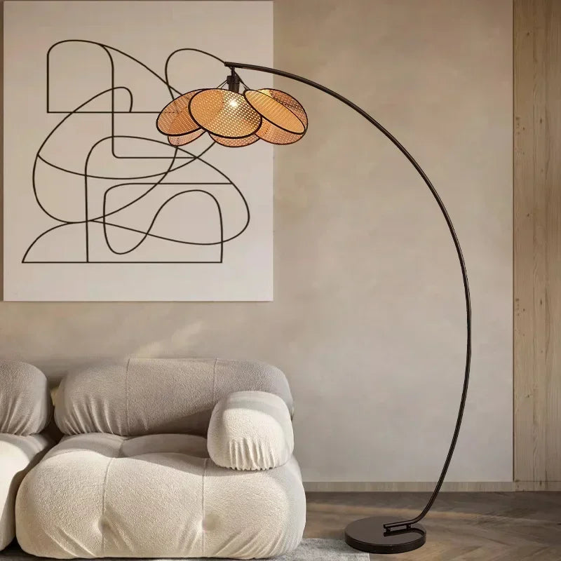  Lampadaire moderne avec base en métal et abat-jour en rotin, posé près d'un canapé design.