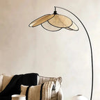 Lampadaire en métal noir avec abat-jour en rotin, installé dans un espace de détente.
