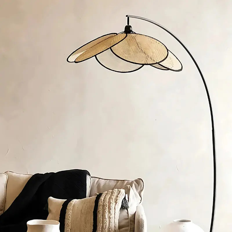Lampadaire en métal noir avec abat-jour en rotin, installé dans un espace de détente.