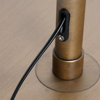 Câble noir connecté à un lampadaire en métal doré avec abat-jour en rotin ajouré