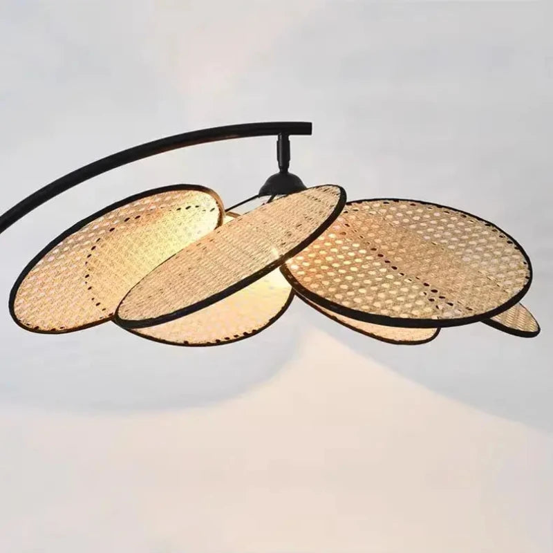 Lampadaire bohème avec un abat-jour en rotin allumé, créant une ambiance chaleureuse.