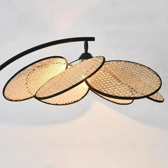 Lampadaire bohème avec un abat-jour en rotin allumé, créant une ambiance chaleureuse.