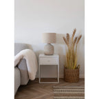 Fauteuil en tissage gris clair avec plaid crème, lampe à poser céramique abat-jour lin écru
