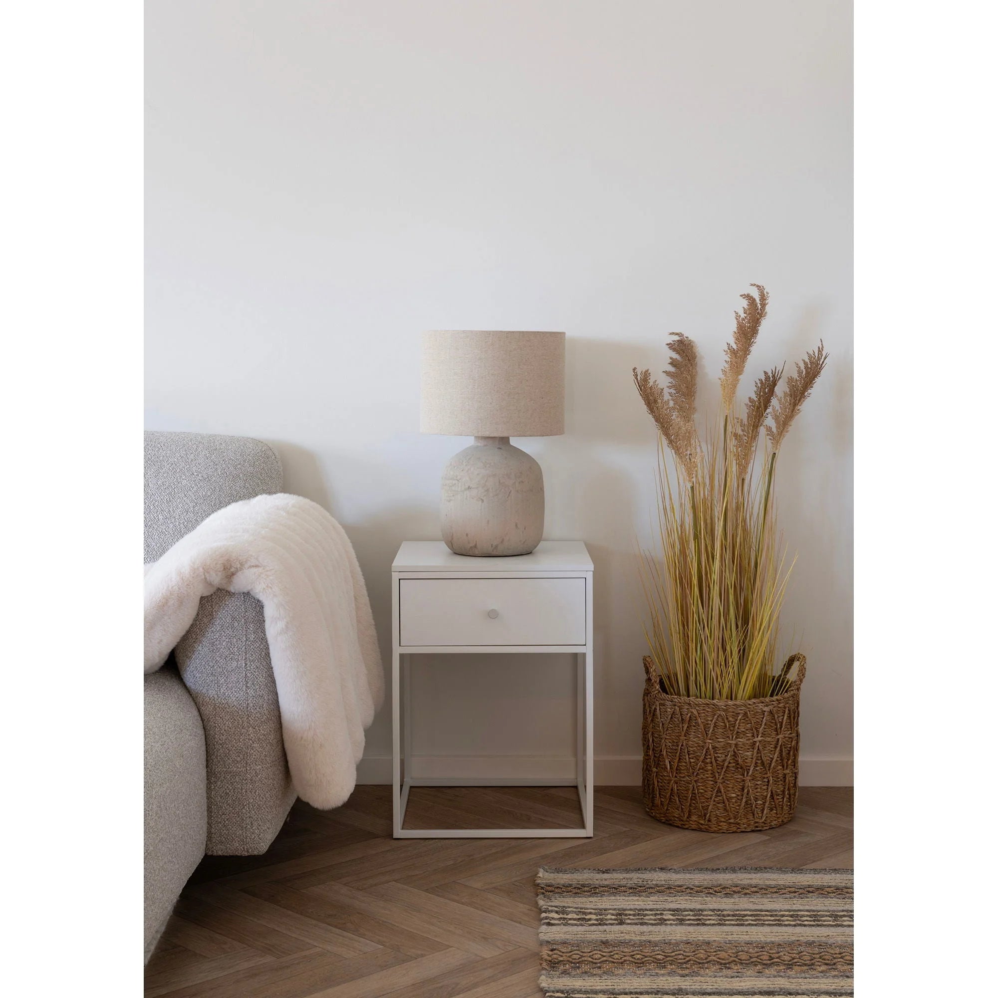 Fauteuil en tissage gris clair avec plaid crème, lampe à poser céramique abat-jour lin écru