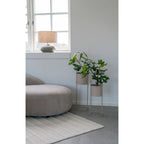 Intérieur avec plantes et mobilier mettant en valeur la lampe en céramique verte et abat-jour beige