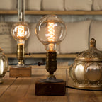 lampe bois vintage allumée avec ampoule ronde filament sur une table