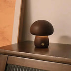 Petite lampe champignon en bois, allumée et posée sur un meuble en bois foncé.