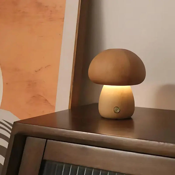 Petite lampe champignon en bois foncé allumée, posée sur un meuble, ambiance tamisée.