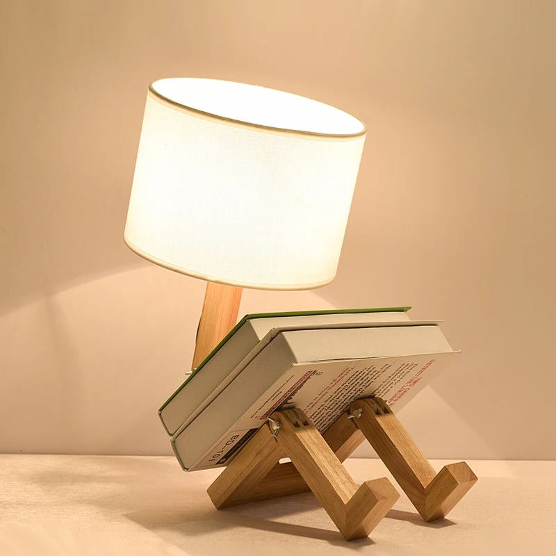 Lampe de chevet bonhomme en bois allumée avec un livre posé sur les jambes en bois