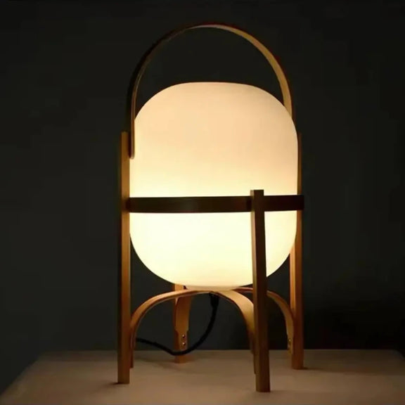 Lampe à pied en bois de taille moyenne avec abat-jour blanc, posée sur un sol en bois.
