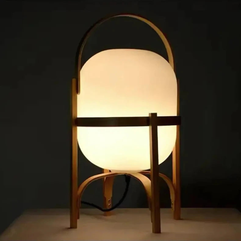 Lampe à pied en bois de taille moyenne avec abat-jour blanc, posée sur un sol en bois.
