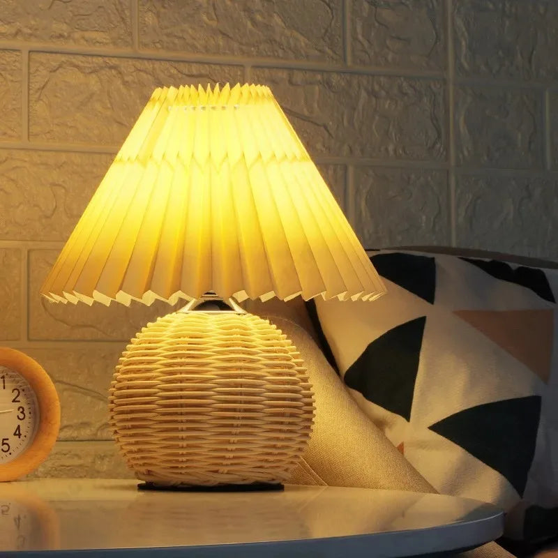 Lampe en rotin vintage avec abat-jour plissé blanc allumée dans une ambiance cosy