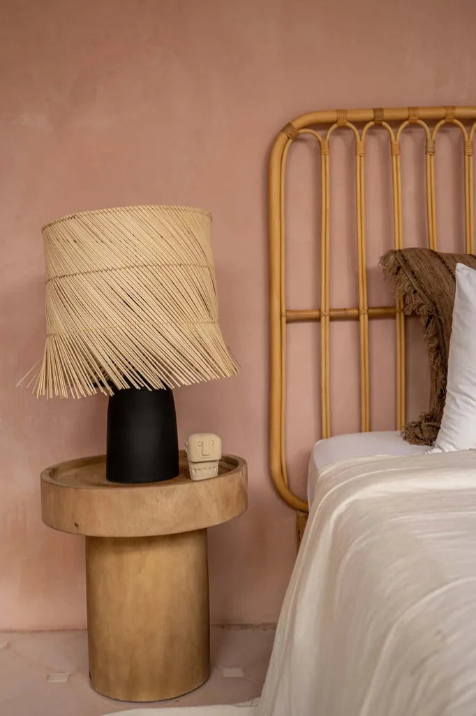 Lampe de table en rotin noir naturel avec abat-jour tissé sur un meuble cylindrique